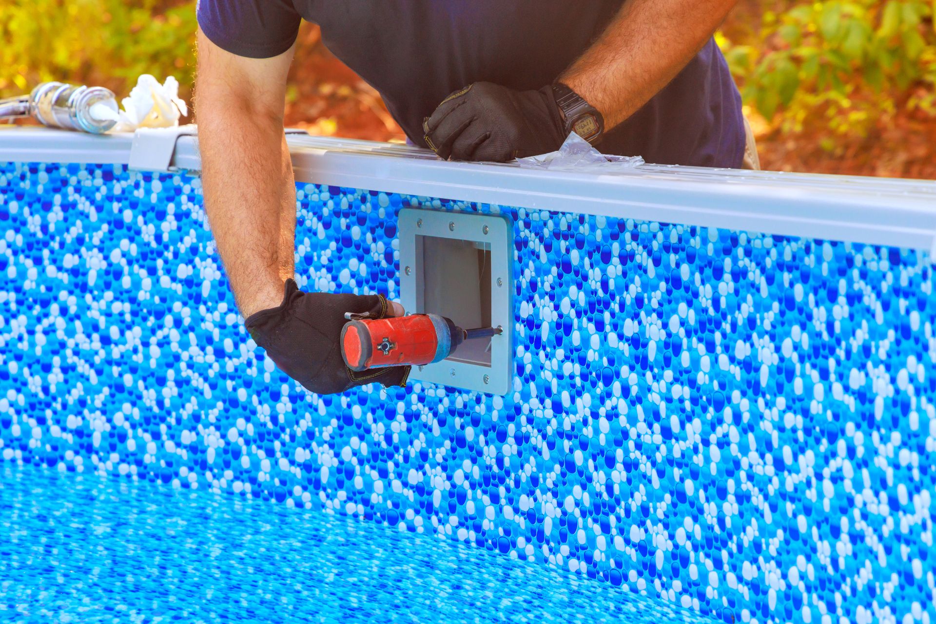 Handwerker montiert Filteranlage im blauen Pool, Beispiel fuer den technischen Aufbau eines Pools mit Pool Komplettset im Garten.